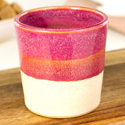 Handmade banded espresso cup close-up showing deep crimson glaze and satin matte sandy base