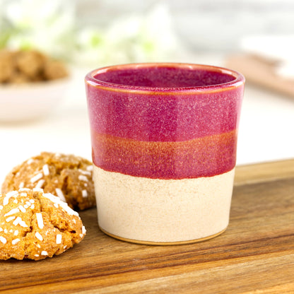 Two-tone ceramic espresso cup in Crimson and sandy oat glaze on wooden board with biscuits