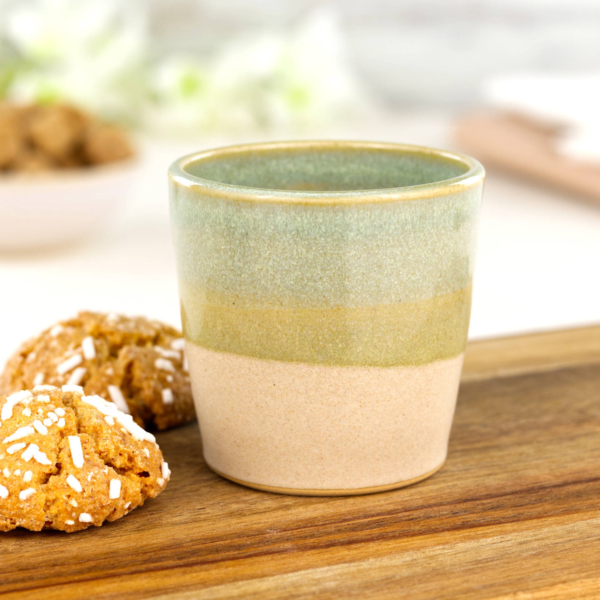 Two-tone ceramic espresso cup in Pale Green and sandy oat glaze styled with biscuits on wooden board