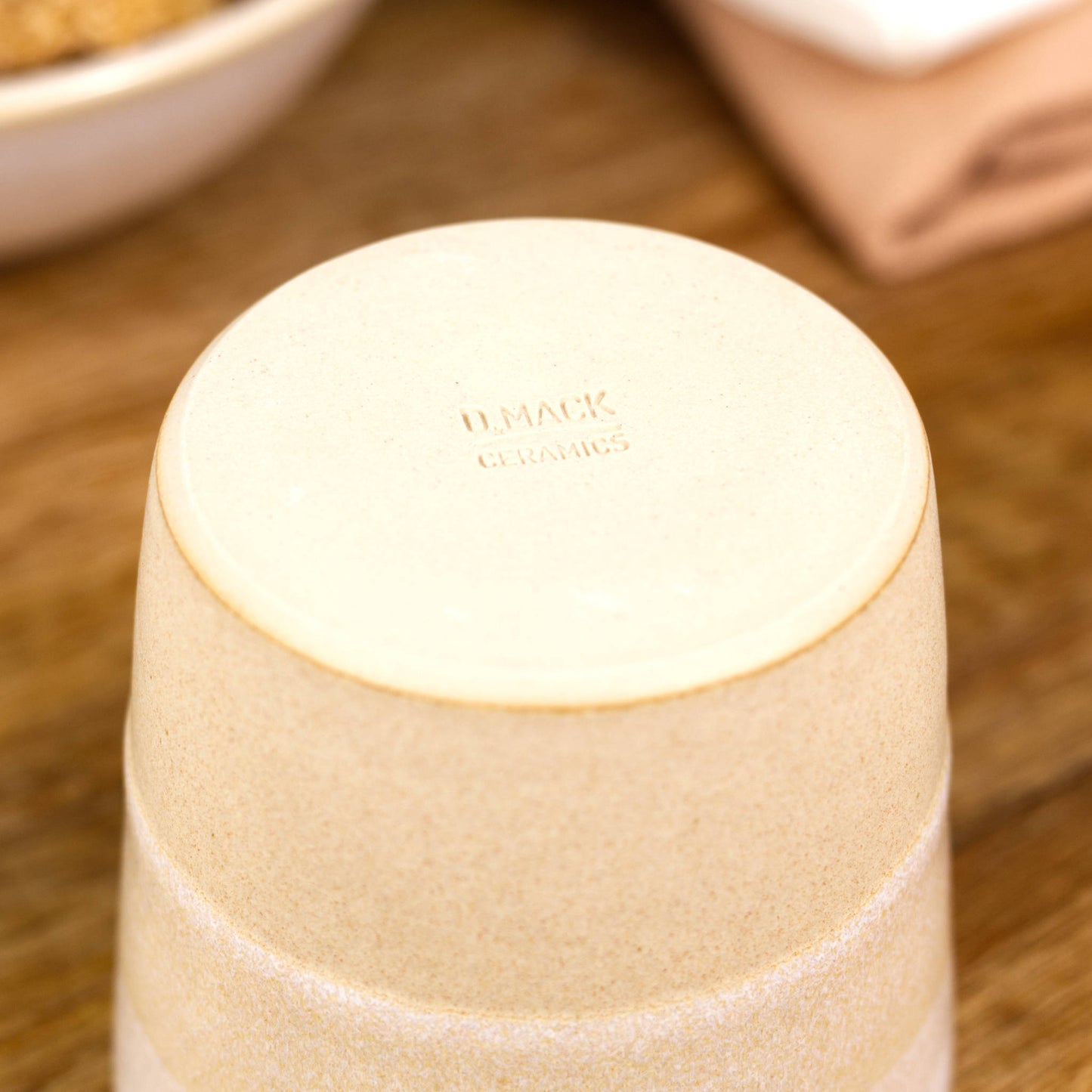 The base of a white and cream coloured espresso tumbler showing the artisan maker's mark