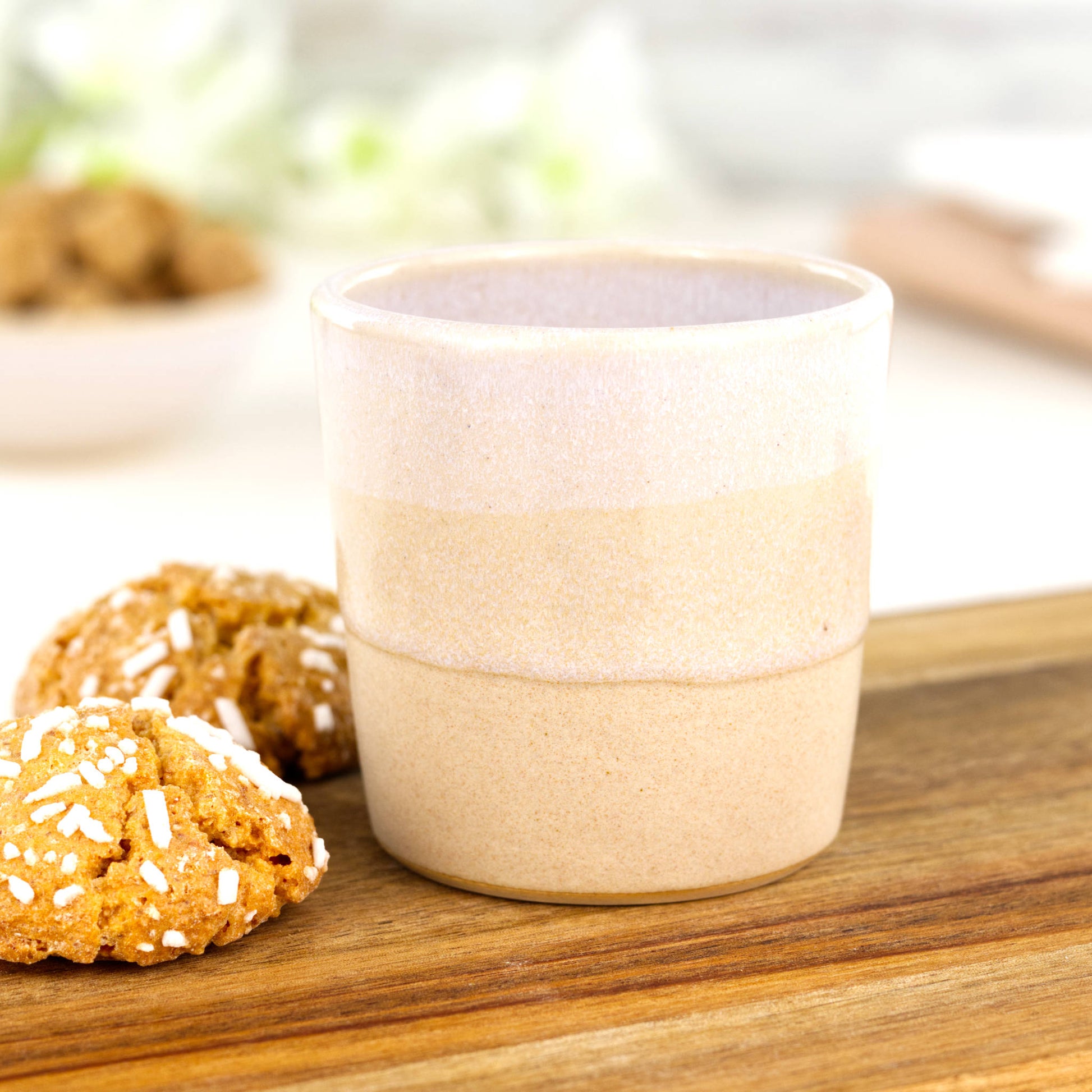 White and cream coloured espresso cup, wheel thrown in a small British studio sits on a wooden plank