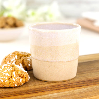 White and cream coloured espresso cup, wheel thrown in a small British studio sits on a wooden plank
