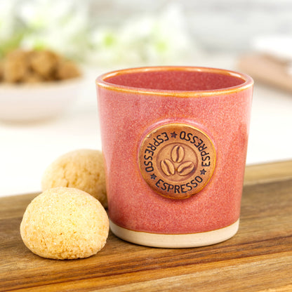 Coral ceramic espresso cup with coffee bean motif styled with biscuits on wooden board