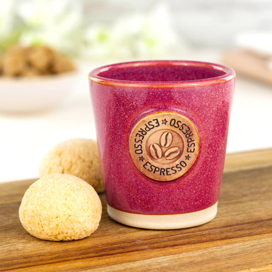 Crimson ceramic espresso cup with coffee bean motif styled with biscuits on wooden board