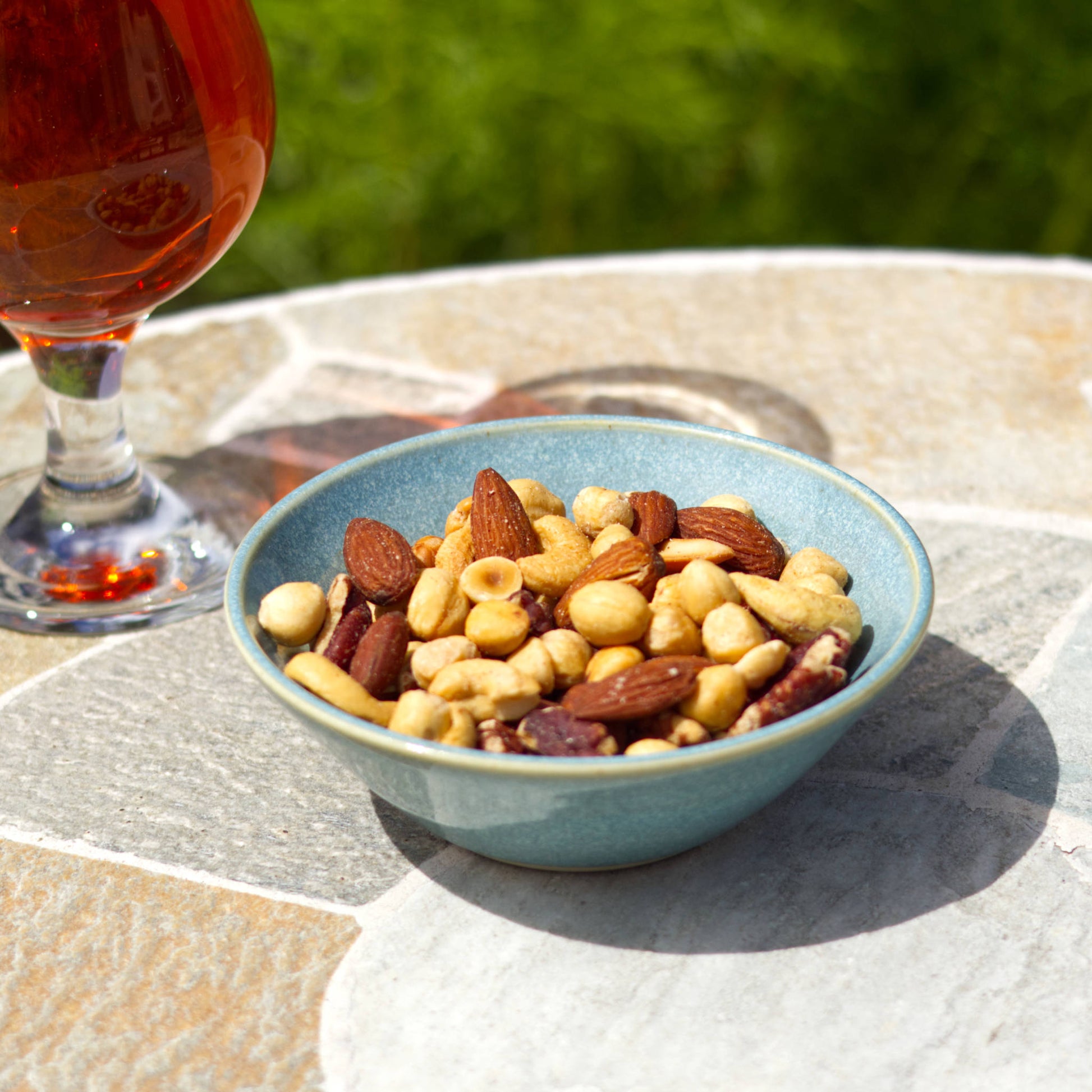 Coastal Blue stoneware snack bowl with mixed nuts beside a drink, handmade in a British pottery studio for barbecues