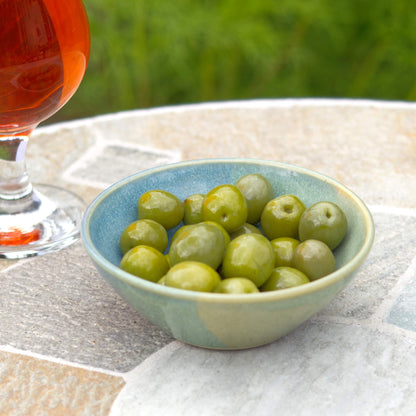 Blue and Green ceramic snack bowl filled with green olives beside a drink, handmade stoneware bowl for aperitivo nibbles, olives and easy summer entertaining