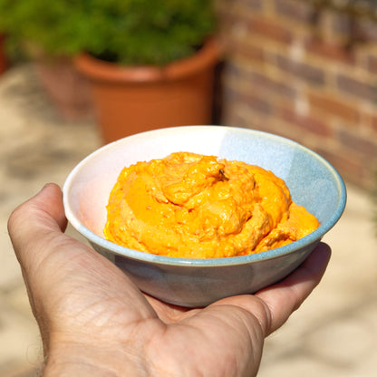 Coastal Blue and White handmade dip bowl held in hand with roasted pepper hummus, a small ceramic bowl for barbecues and garden lunches