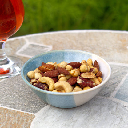 Coastal Blue and White stoneware nibbles bowl with mixed nuts beside a drink, wheel-thrown pottery for sharing food outdoors