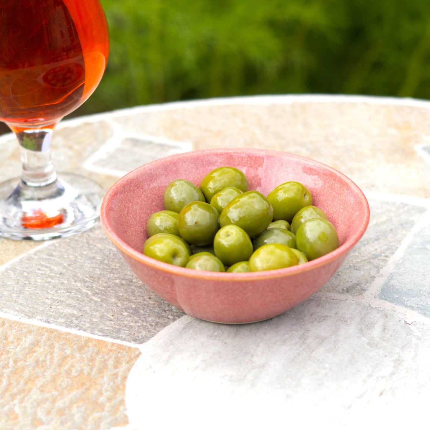 Coral handmade ceramic olive bowl filled for garden drinks, a small stoneware snack bowl for barbecues and relaxed entertaining