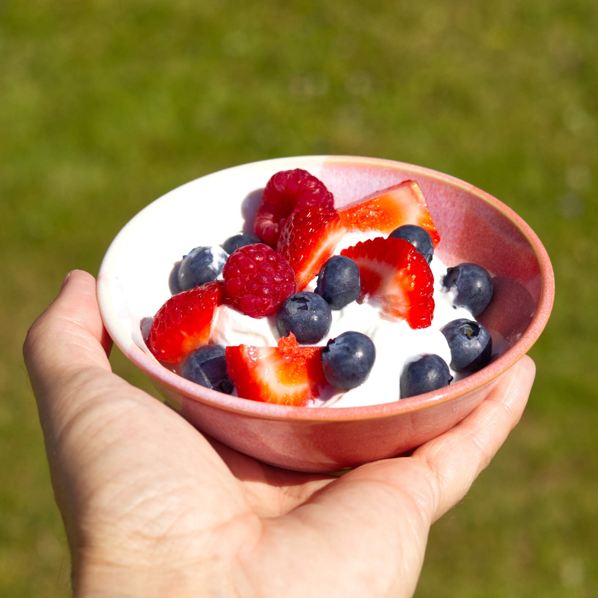 Coral and White handmade small bowl filled with yoghurt, strawberries, raspberries and blueberries, a wheel-thrown stoneware breakfast bowl for summer brunch and alfresco dining