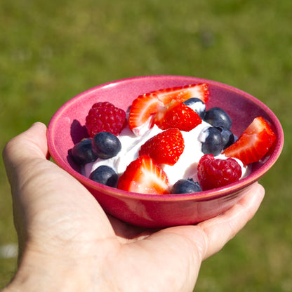 Crimson handmade ceramic dessert bowl held in hand with yoghurt and summer berries, a small stoneware bowl for alfresco eating
