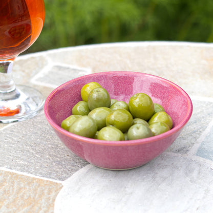 Crimson handmade olive bowl on stone table beside a drink, small pottery snack bowl for garden parties and evening nibbles