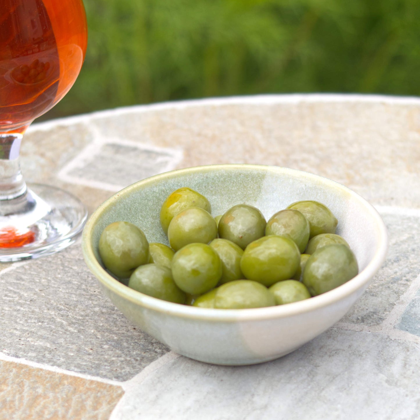 Pale Green and White handmade stoneware olive bowl on a patio table, a wheel-thrown small bowl for garden drinks, tapas and summer entertaining
