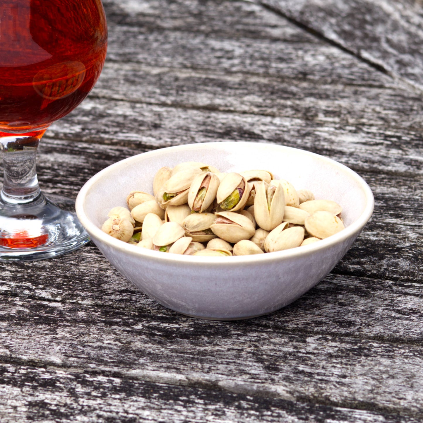 White pottery nibbles bowl with pistachios beside a drink, handmade in a small British studio for easy entertaining