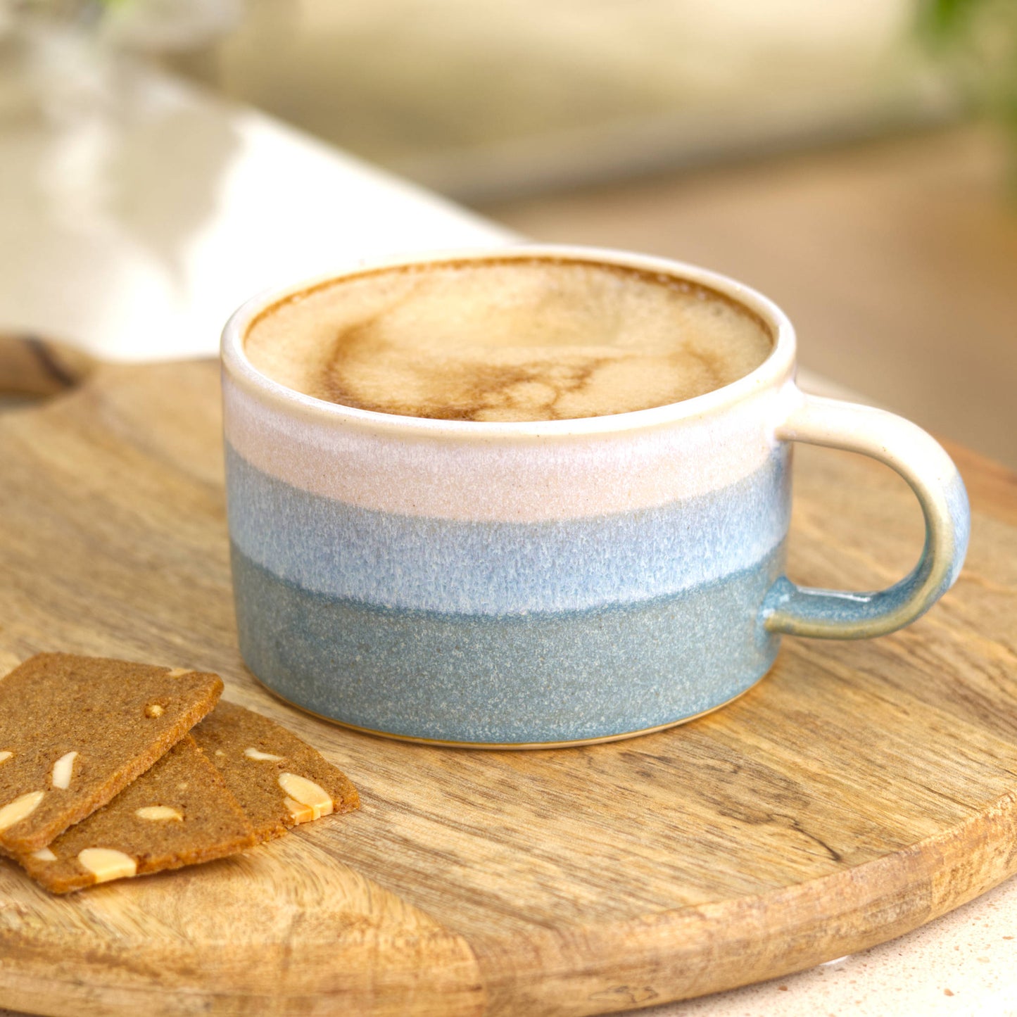 Flat white coffee paired with almond thin biscuits on a wooden board in a cosy kitchen