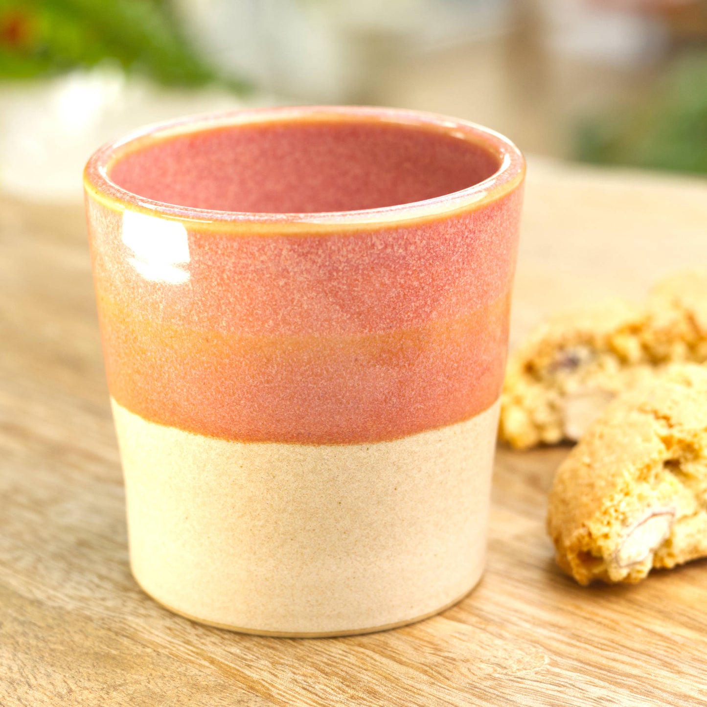 Coral two-tone espresso cup styled in kitchen setting with biscotti for casual coffee break