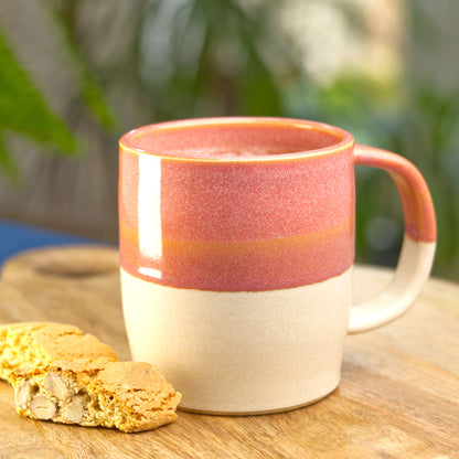 Coral and Sand handmade hot chocolate mug filled with frothy coffee on a wooden board with biscotti, wheel-thrown stoneware made in my Sussex pottery studio