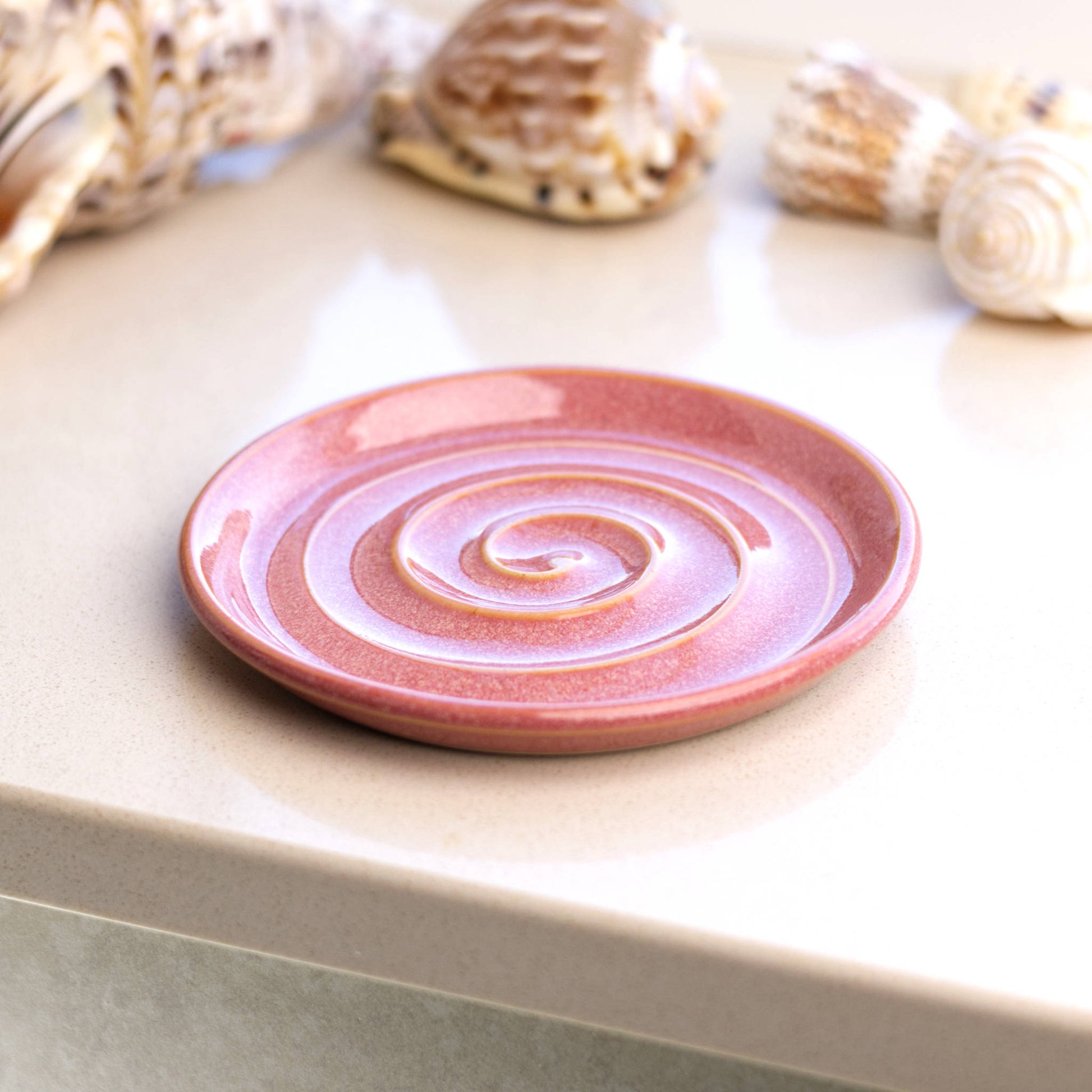 Coral ceramic soap dish on bathroom windowsill, handmade spiral soap tray adding warm tone to bathroom décor