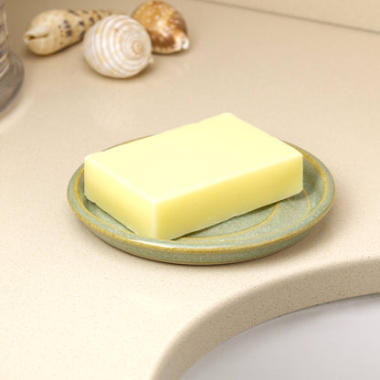 Handmade pale green pottery soap tray with cream soap on basin shelf