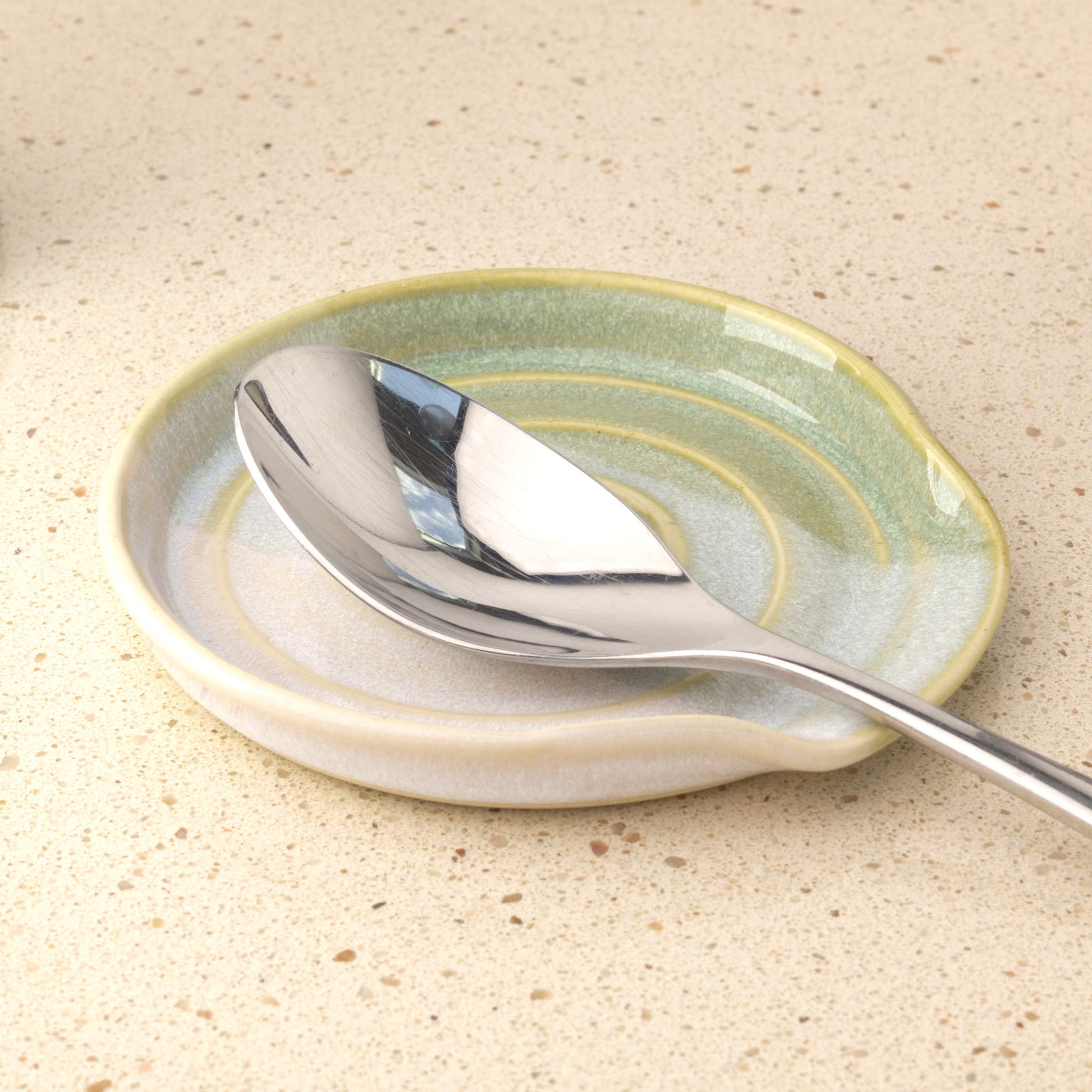 Pale Green and White ceramic spoon rest holding serving spoon, practical handmade kitchen accessory for clean worktops