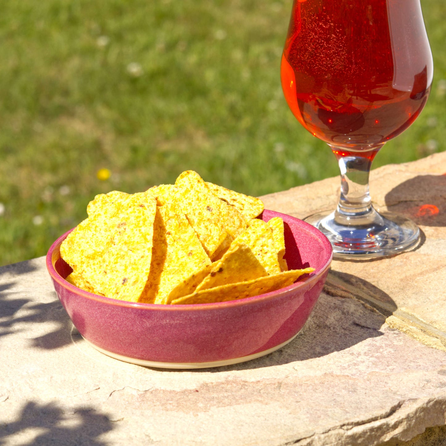 Crimson handmade tapas bowl filled with tortilla chips, styled outdoors for party snacks, BBQ nibbles, sharing food and relaxed summer entertaining