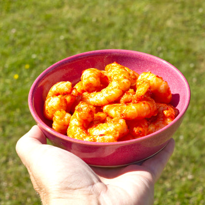 Handmade Crimson ceramic tapas bowl held in the hand and served with prawns, a shallow stoneware dish for seafood starters, small plates and alfresco dining