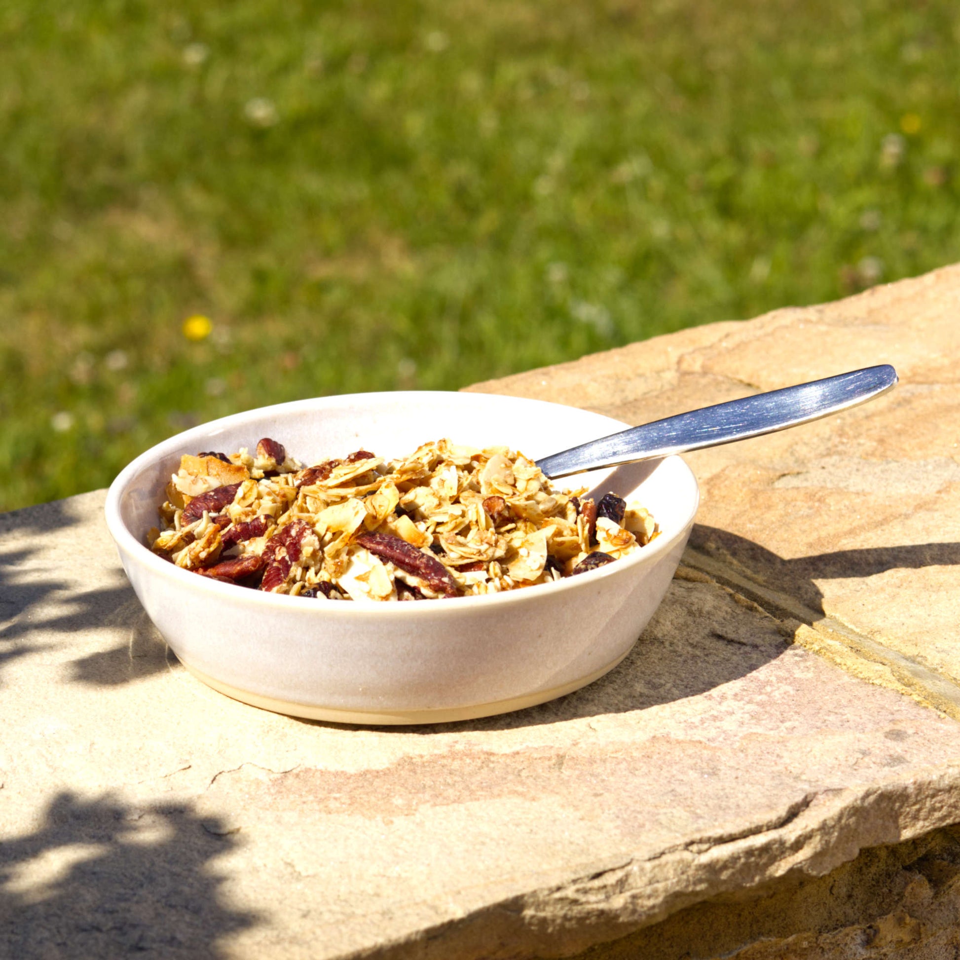 White handmade tapas bowl filled with granola and a spoon, styled outdoors for light breakfasts, brunch, farmhouse tableware and relaxed alfresco dining