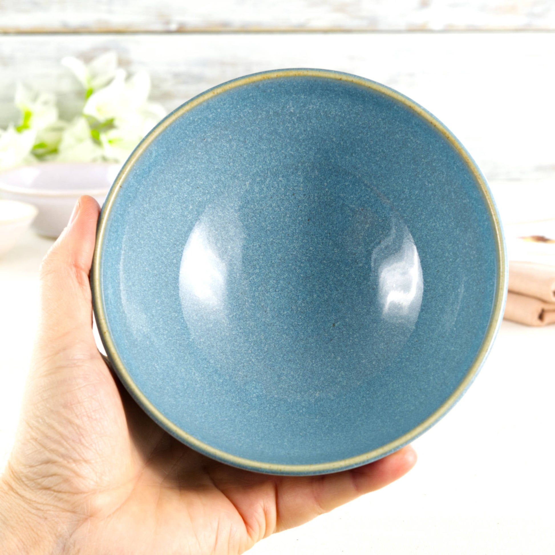Medium ceramic bowl held in the hand, glazed in Coastal Blue with a rich sea-inspired finish, ideal for everyday meals, noodles or generous breakfast bowls