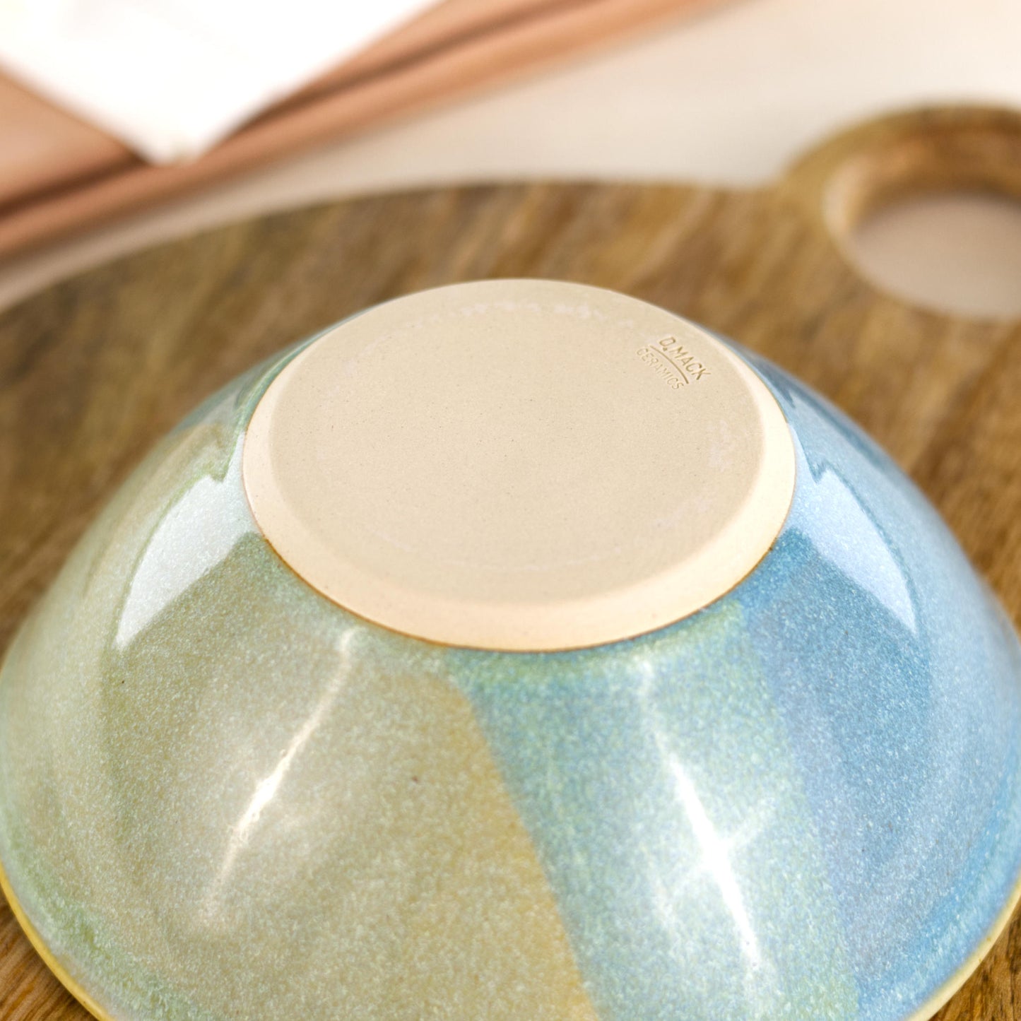 Base of a handmade pottery bowl in Coastal Blue & Pale Green, featuring the D Mack Ceramics makers mark and a smooth burnished underside designed to help protect tabletops