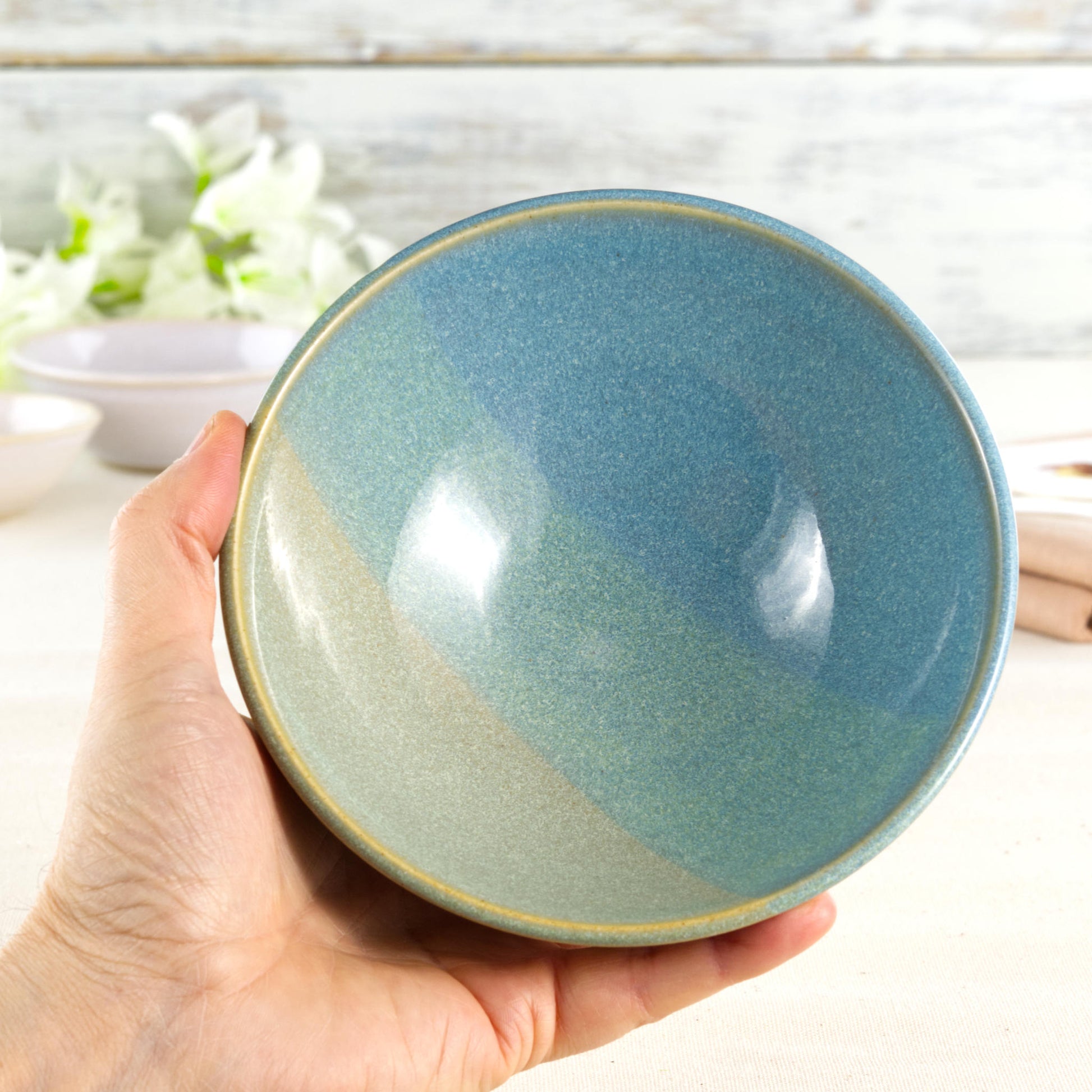 Handmade ceramic serving bowl held in the hand, finished in Coastal Blue & Pale Green glazes with a glossy interior and calming sea-inspired colours