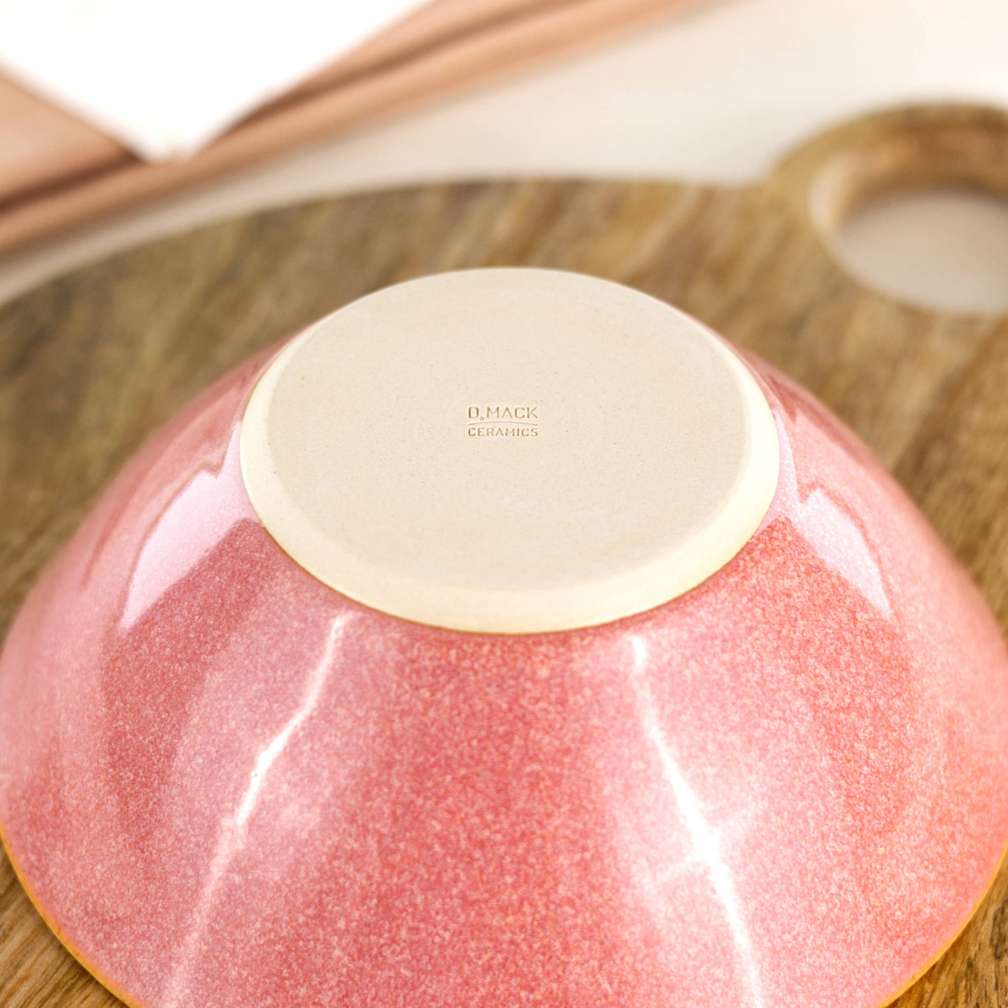 Base of a handmade ceramic bowl in Coral, featuring the D Mack Ceramics makers mark and a smooth burnished underside to help protect wooden and stone surfaces