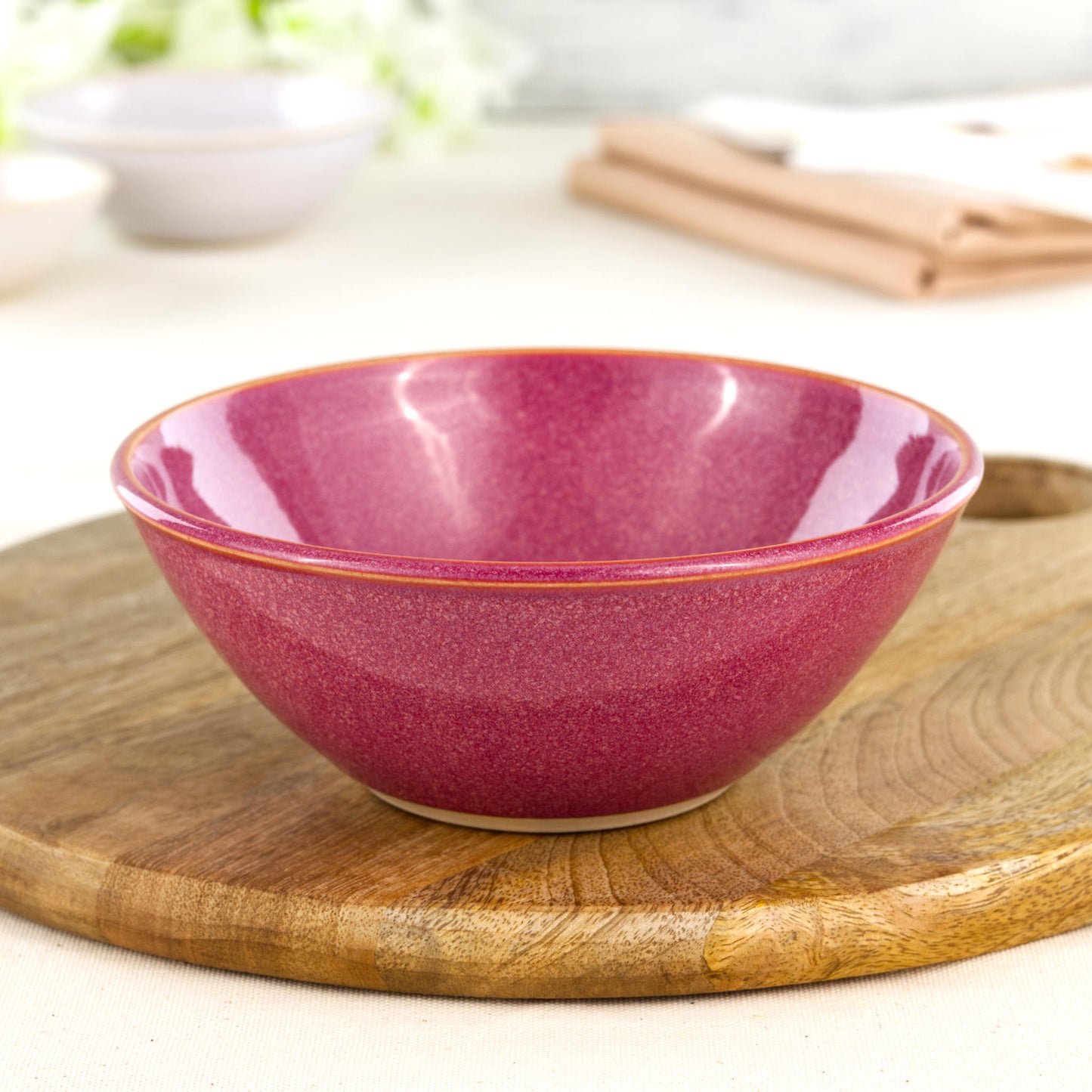 Wheel-thrown Crimson medium bowl on a wooden board, handcrafted in a Sussex ceramic studio and designed for pasta, salads or relaxed modern tableware