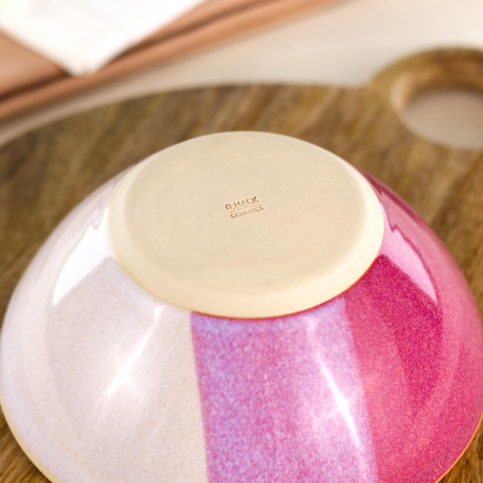 Base of a wheel-thrown medium ceramic bowl in Crimson & White, showing the D Mack Ceramics makers mark and smooth burnished foot to help reduce surface scratching