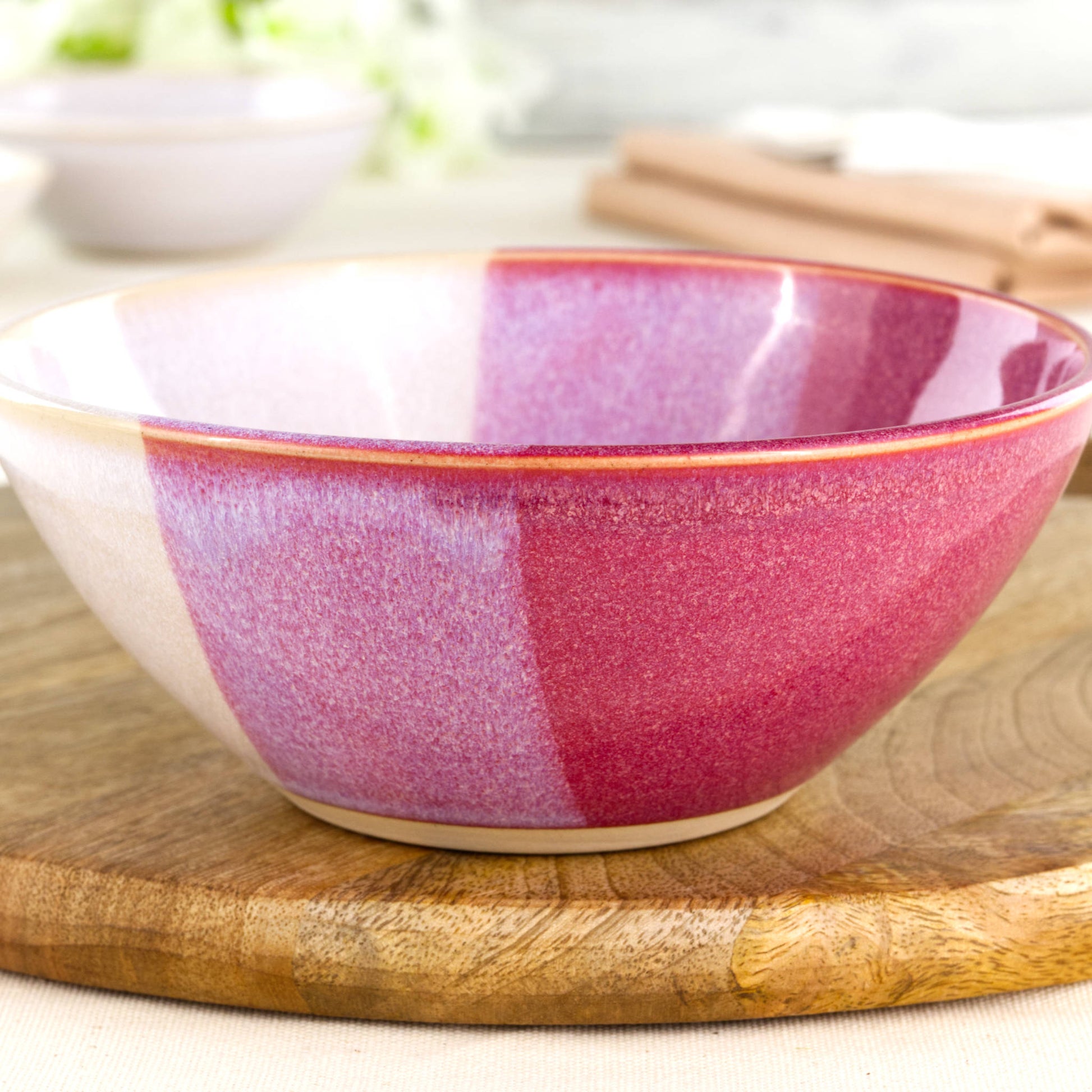 Close-up of a handmade stoneware bowl in Crimson & White, with glossy layered red and soft white glazes across a gently curved medium pottery bowl