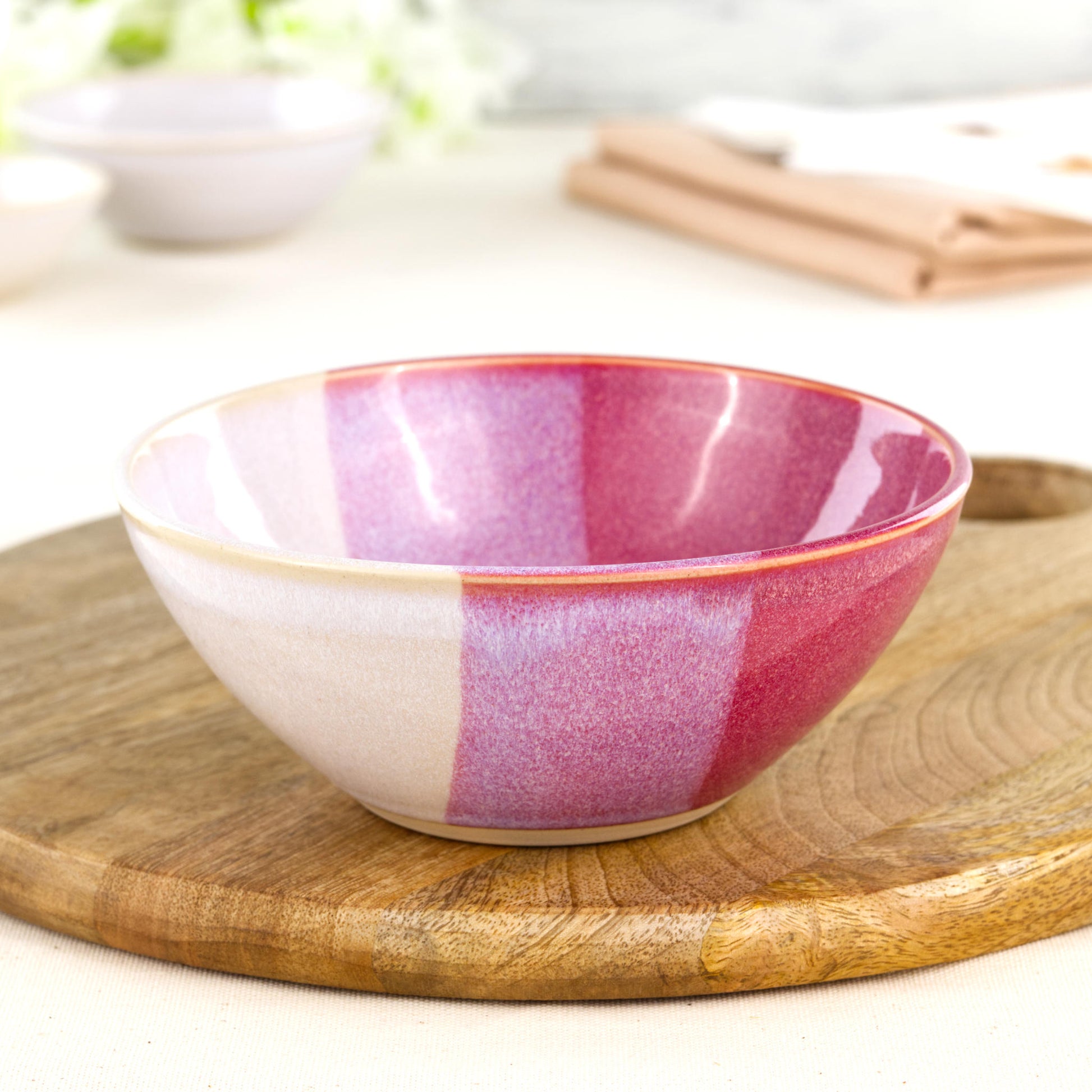 Wheel-thrown medium stoneware bowl in Crimson & White on a wooden board, ideal as a handmade pasta bowl, salad bowl or colourful pottery serving bowl