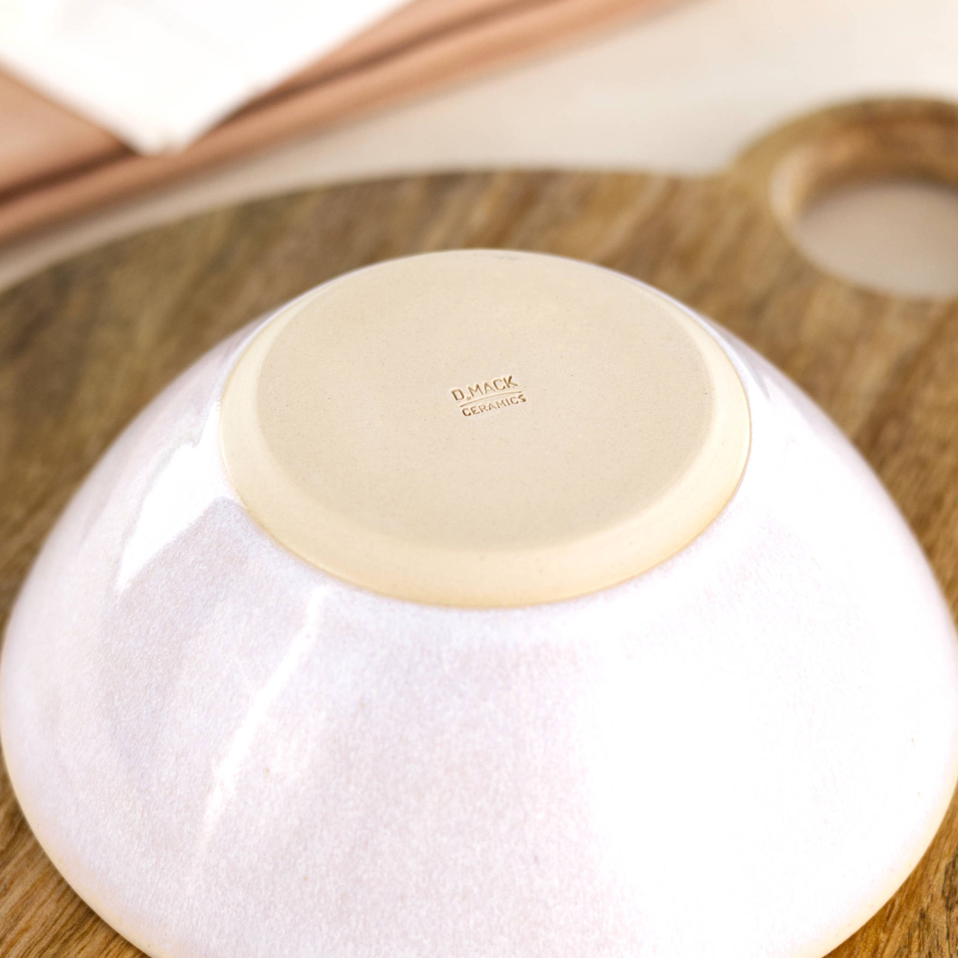 Base of a handmade white ceramic bowl, showing the D Mack Ceramics makers mark and smooth burnished foot, made in a small Sussex pottery studio
