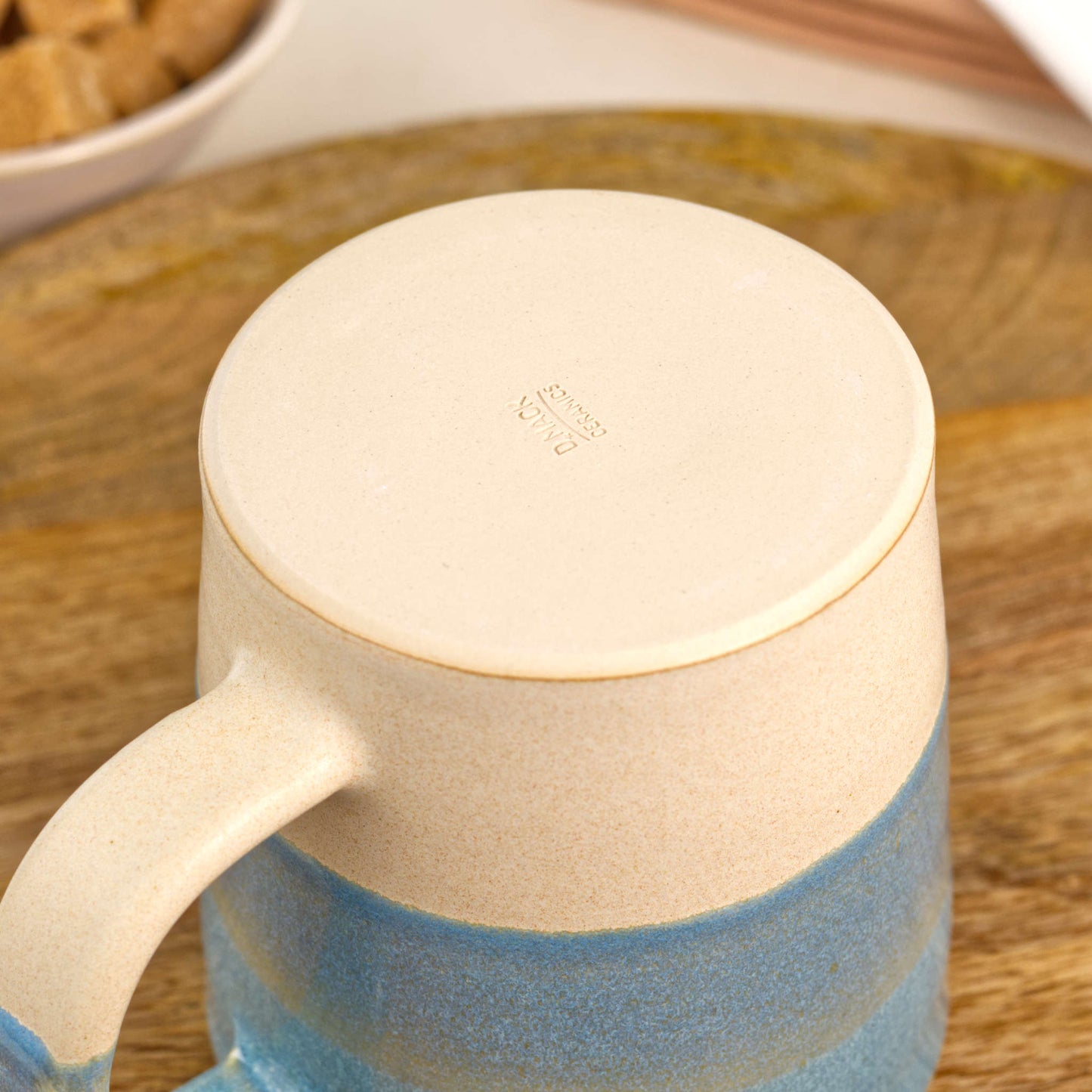 Underside of Coastal Blue and Sand pottery mug showing the burnished smooth base and maker’s mark, handmade in my British pottery studio
