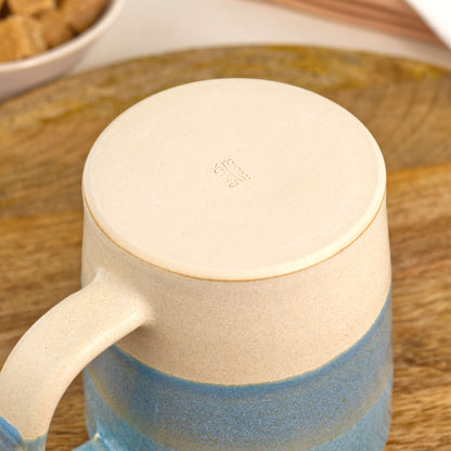 Underside of Coastal Blue and Sand pottery mug showing the burnished smooth base and maker’s mark, handmade in my British pottery studio
