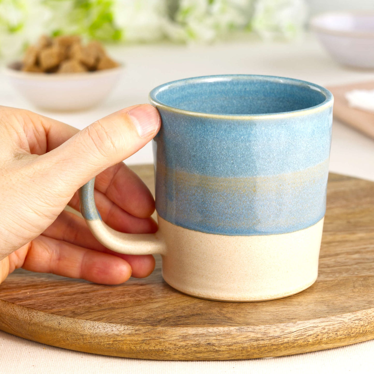 Coastal Blue and Sand stoneware mug shown in hand, highlighting the comfortable handle and tactile feel of this handmade coffee mug