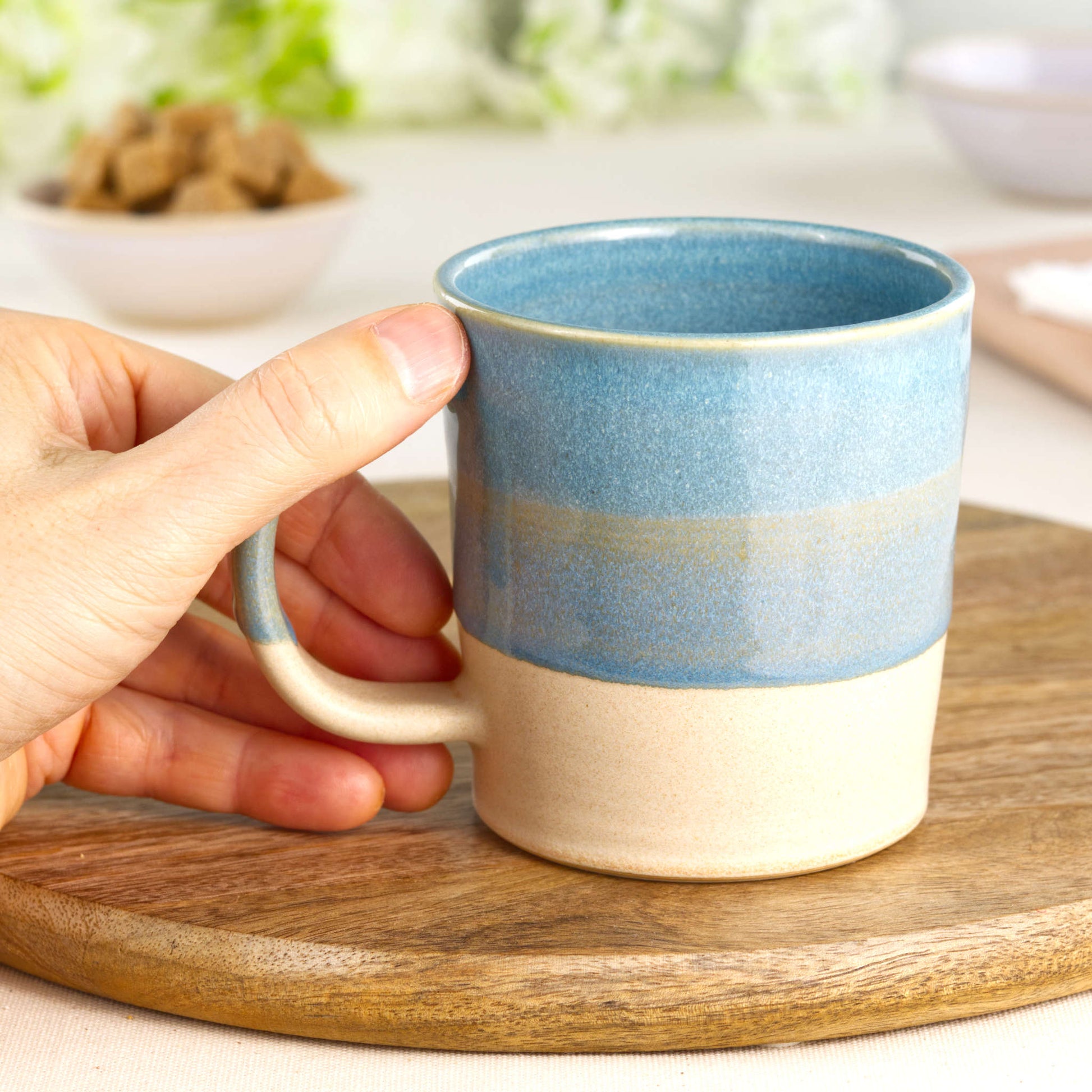 Coastal Blue and Sand stoneware mug shown in hand, highlighting the comfortable handle and tactile feel of this handmade coffee mug