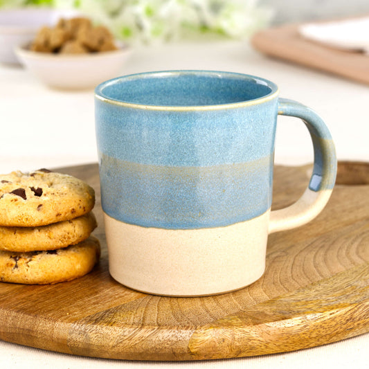 Coastal Blue and Sand artisan pottery mug on a wooden board with cookies, a wheel-thrown everyday mug made in my small UK studio
