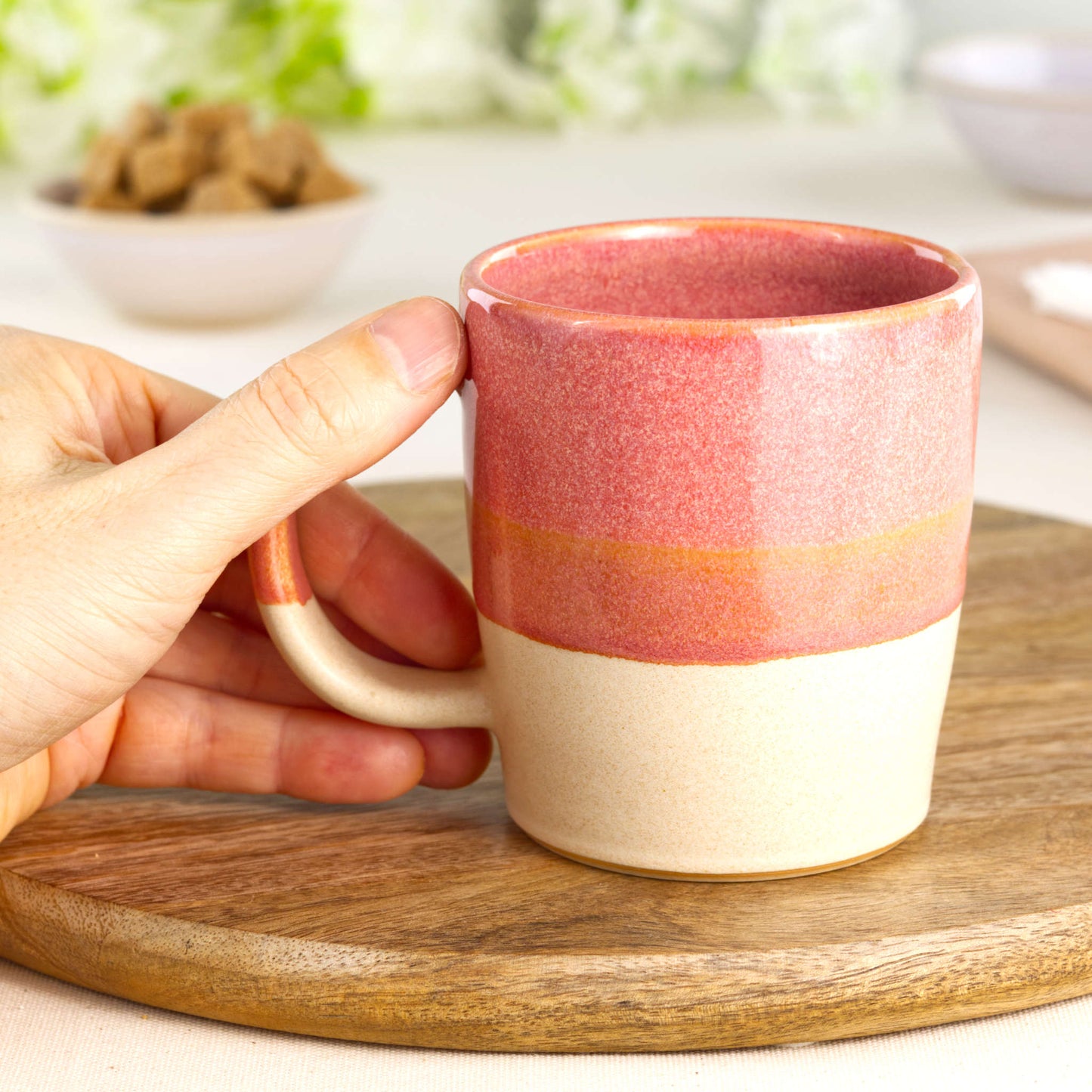 Coral and Sand wheel-thrown tea mug shown in hand, highlighting the comfortable handle and tactile feel of this everyday pottery mug from my small UK studio