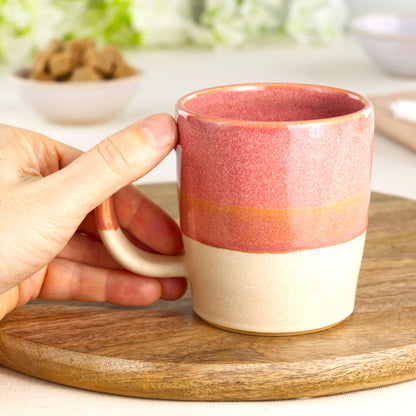 Coral and Sand wheel-thrown tea mug shown in hand, highlighting the comfortable handle and tactile feel of this everyday pottery mug from my small UK studio