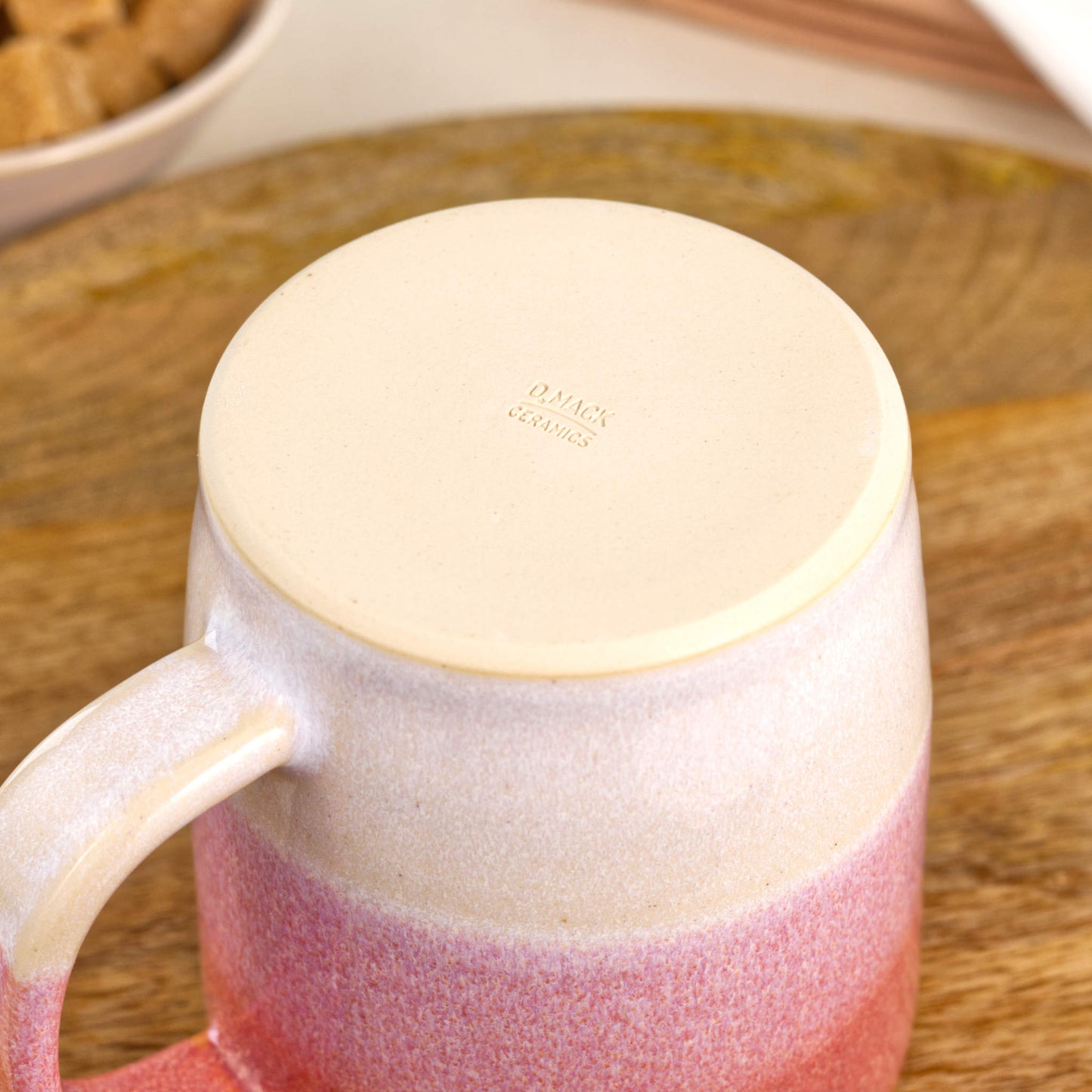 Underside of Coral and White stoneware mug showing the burnished smooth base and maker’s mark from my home pottery studio
