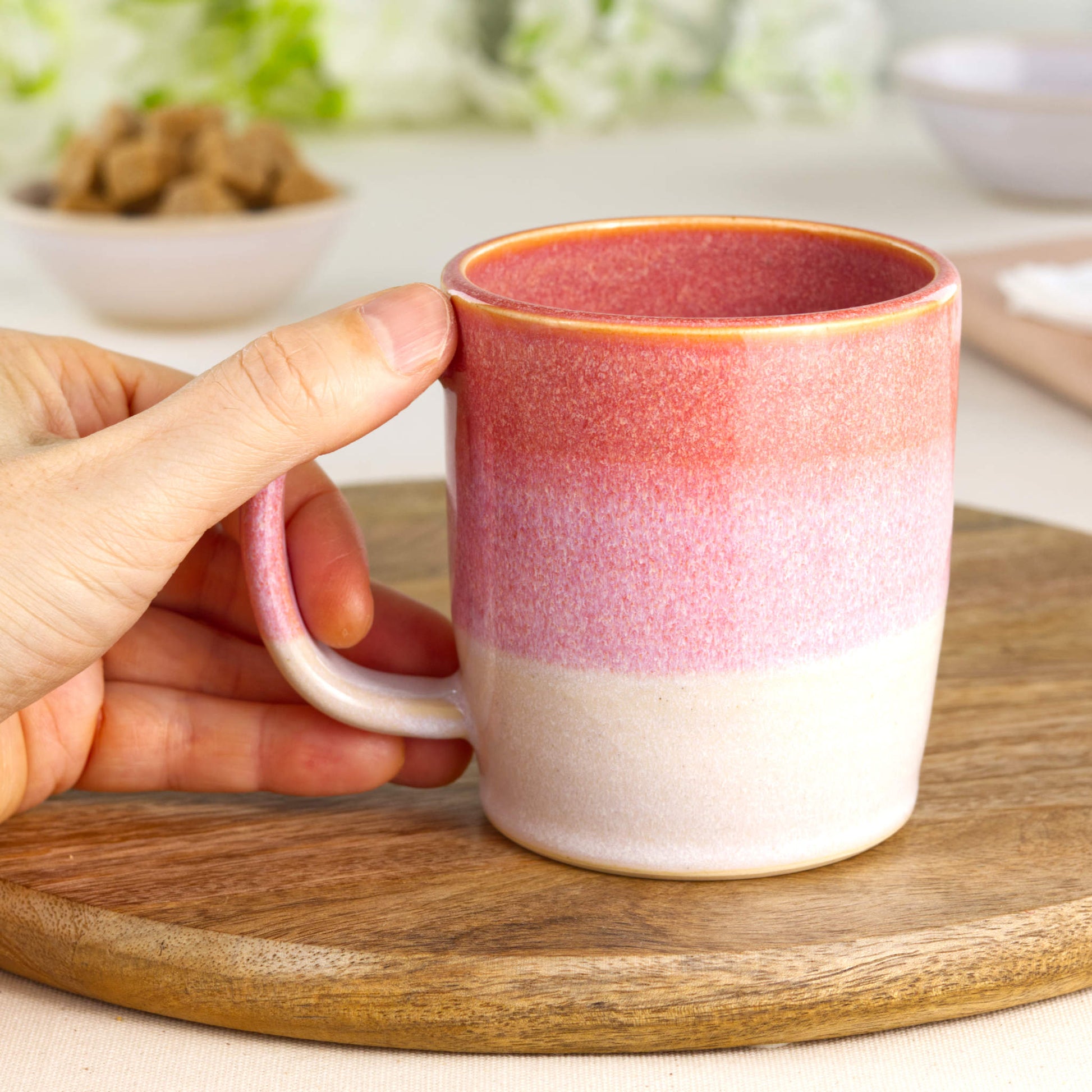 Coral and White pottery mug shown in hand, highlighting the comfortable handle and warm character of this handmade tea cup