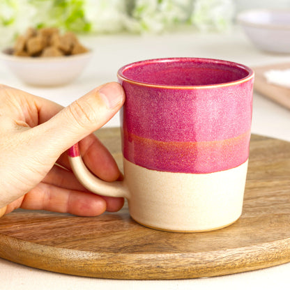 Crimson and Sand wheel-thrown tea mug shown in hand, highlighting the comfortable handle and tactile feel of this everyday pottery mug from my small UK studio
