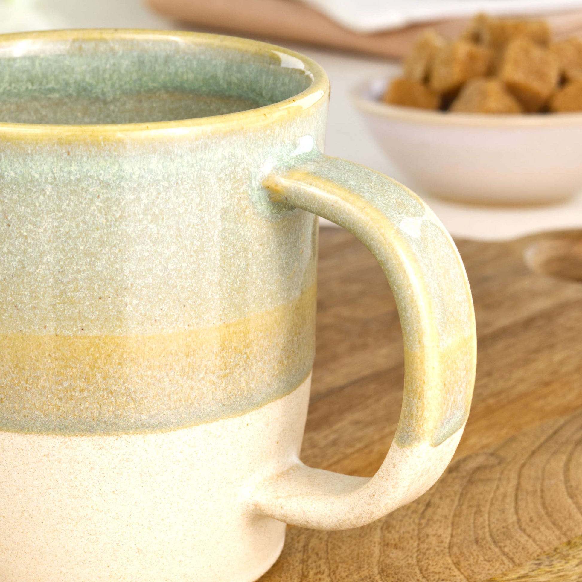 Close-up of the handle on a Pale Green and Sand handmade coffee mug, finished with my Sea Smoothed Pebble glaze above a sandy satin-matte base in my home studio