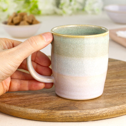 Wheel-thrown stoneware mug in Pale Green and White shown in hand, highlighting the comfortable handle and everyday shape