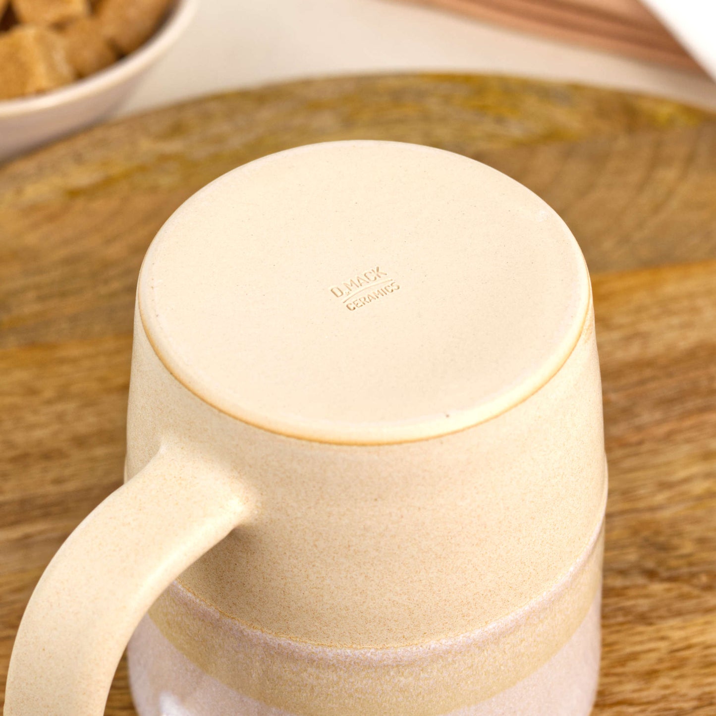 Underside of White and Sand pottery mug showing the burnished smooth base and maker’s mark, a handmade beige and cream ceramic mug from my British pottery studio