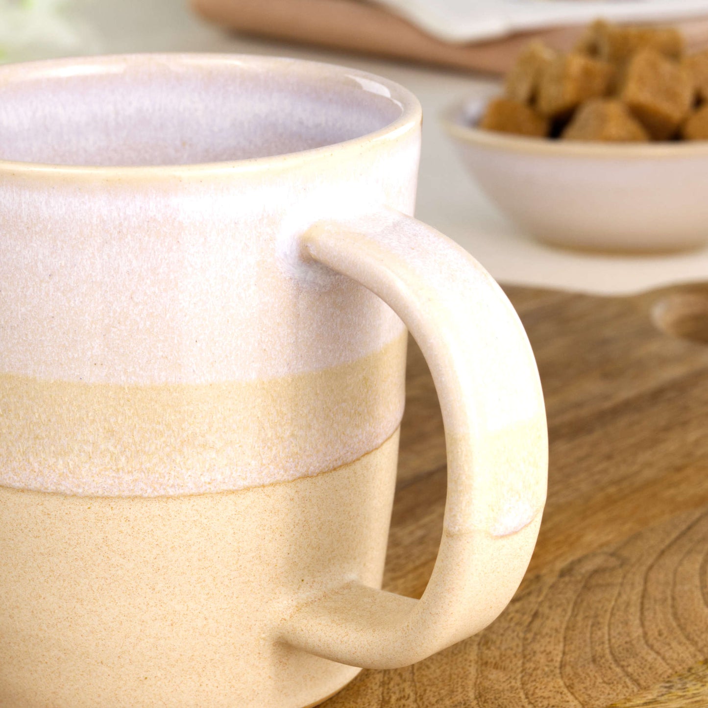 Close-up of the handle on a White and Sand handmade coffee mug, finished with glossy white glaze above a sandy satin-matte base for a clean minimalist look
